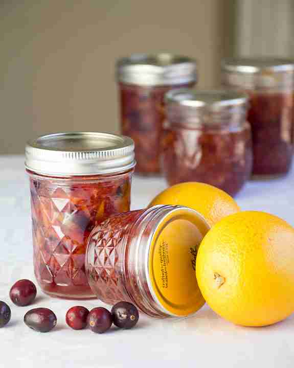 Orange cranberry marmalade in jars with fresh oranges