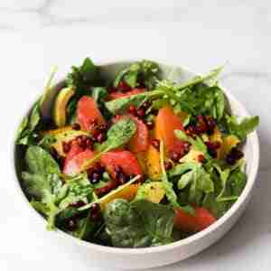 citrus arugula (rocket) salad with grapefruit and orange in white bowl