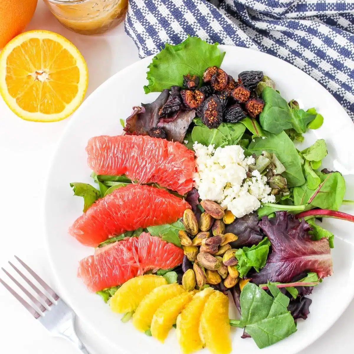 winter citrus and green salad on plate with fresh orange and blue checked cloth