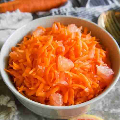 raw carrot salad with grapefruit in a white bowl