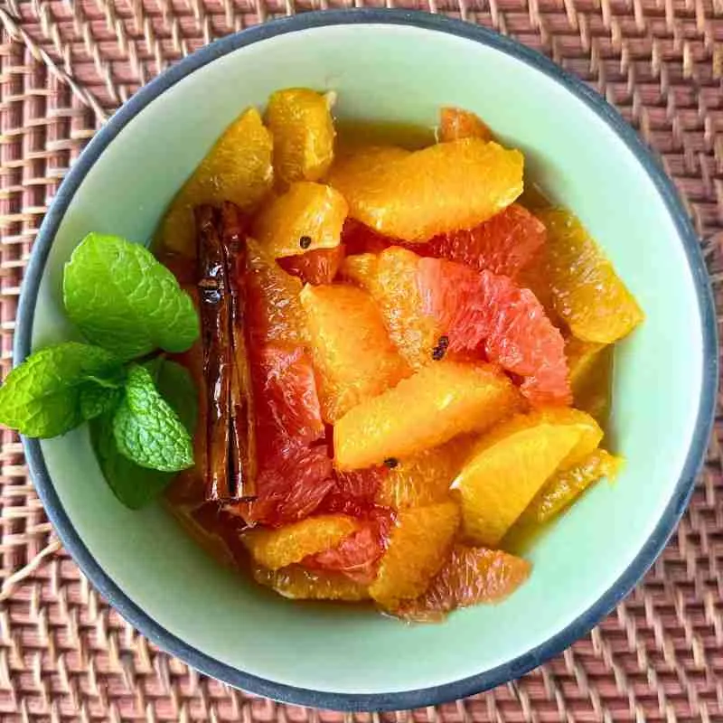 citrus fruit salad in a green Japanese bowl on a rattan mat