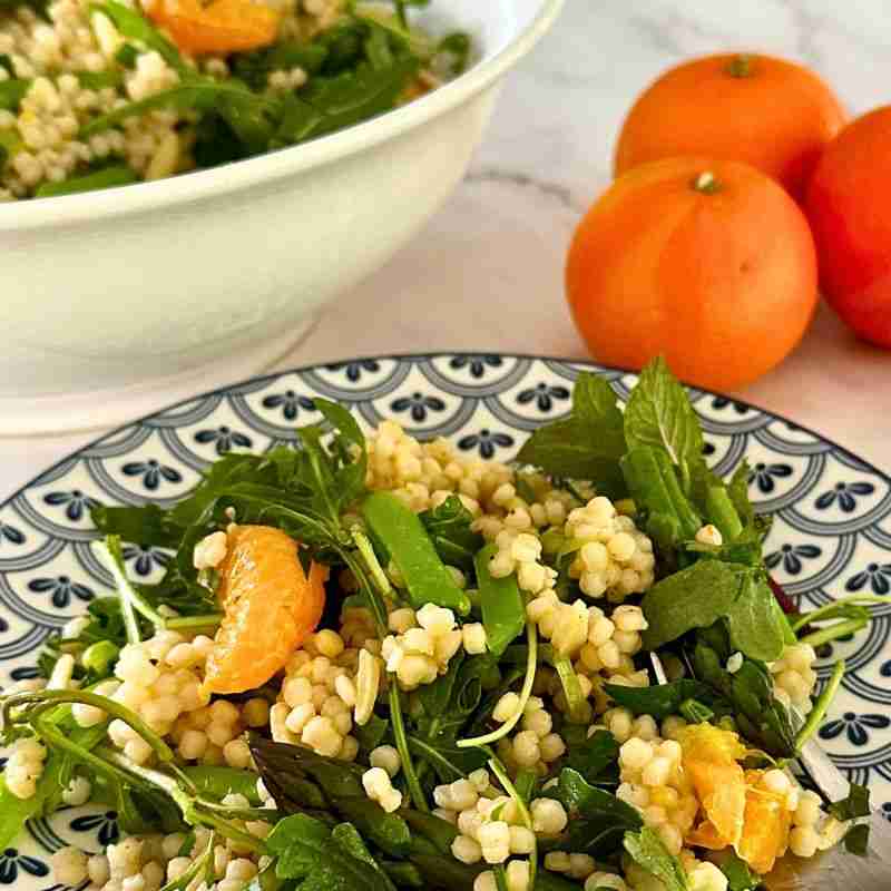 mandarin orange and pearl couscous salad with greens on blue and white plate with fresh mandarins