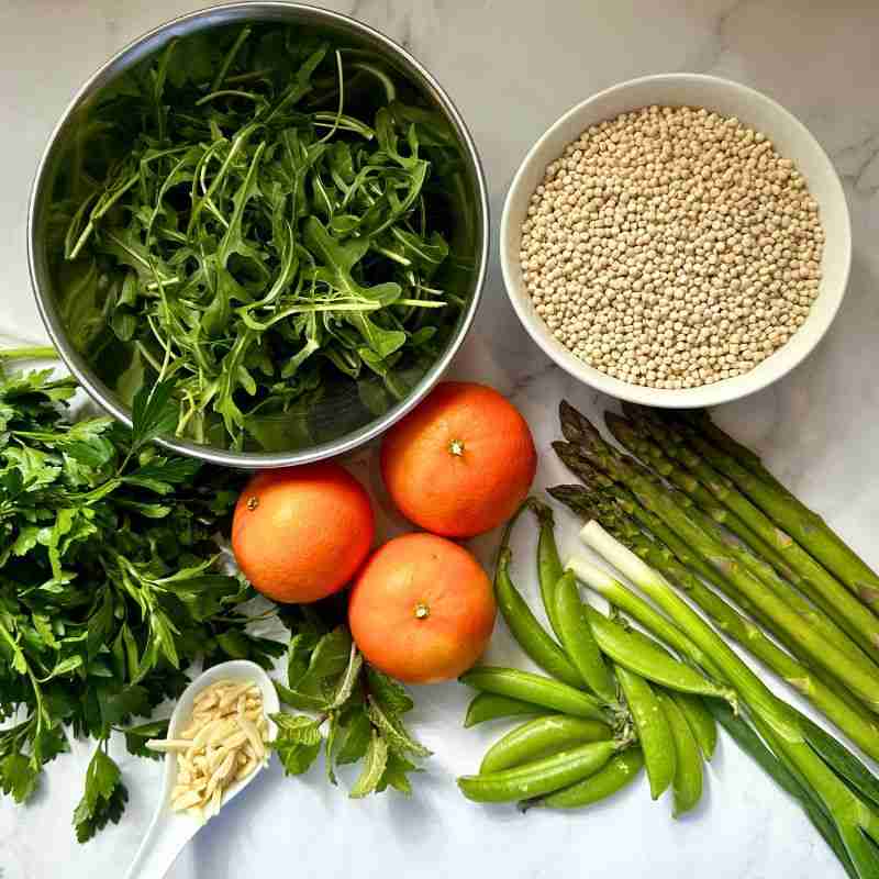 mandarin orange and pearl couscous salad ingredients including rocket, couscous, mandarins, herbs, almonds and fresh green vegetables