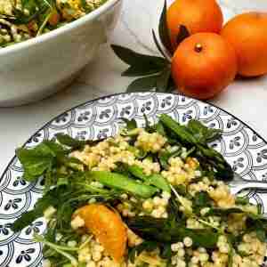 mandarin orange and pearl couscous salad with greens on blue and white plate