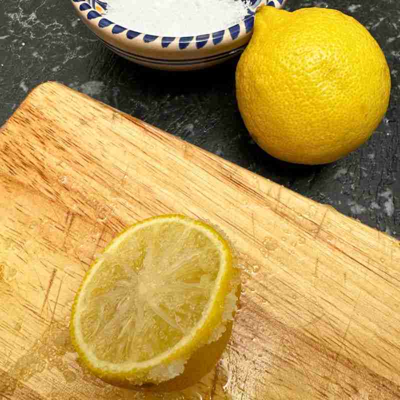 using fresh lemon half and salt to clean a wooden chopping board 