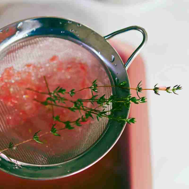 sieve with grapefruit pulp and thyme sprigs 
