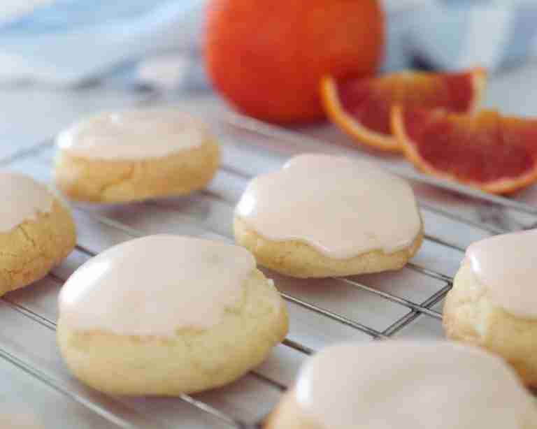 blood orange cookies with citrus icing on cooling rack with fresh blood orange
