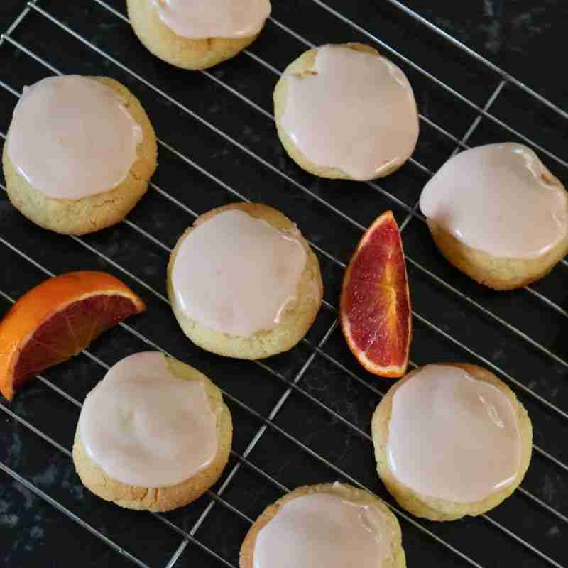 blood orange ccokings with pink blood orange icing on wire rack with fresh blood orange wedges