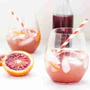 sparkling blood orange shrub cocktail in glass with striped straw