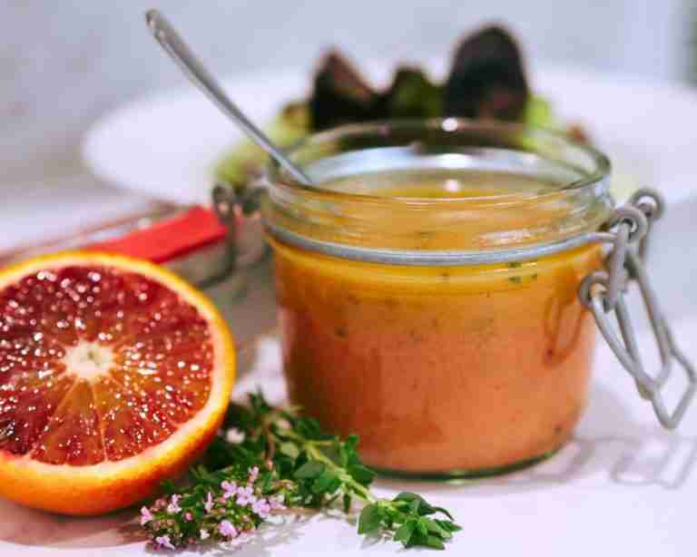 blood orange vinaigrette salad dressing in glass jar with fresh thyme and blood orange half
