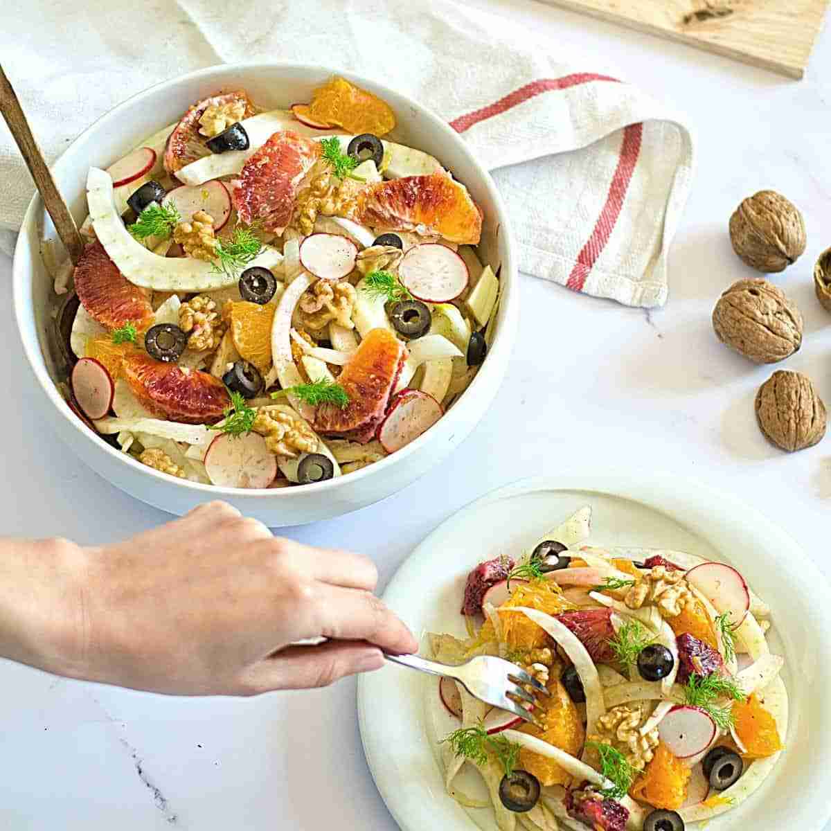 blood orange ad fennel salad with radish and olives in white bowl with walnuts