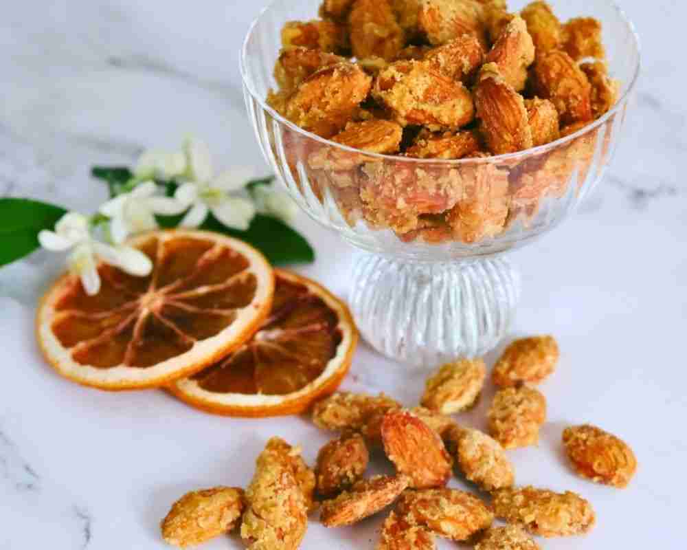 orange candied almonds in glass disg with dried orange slices and orange blossom