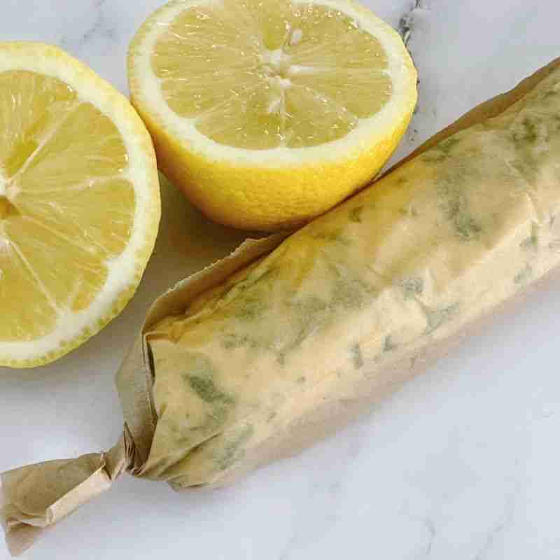compound lemon garlic buttter rolled and wrapped in parchment paper with fresh lemons