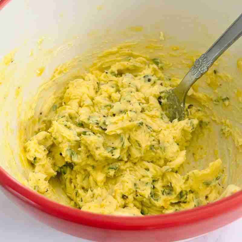 mixing compound orange butter with pepper and rosemary in a bowl