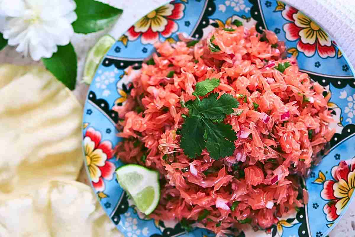 spicy pomelo salad with chili on blue floral plate with lime and pappadams
