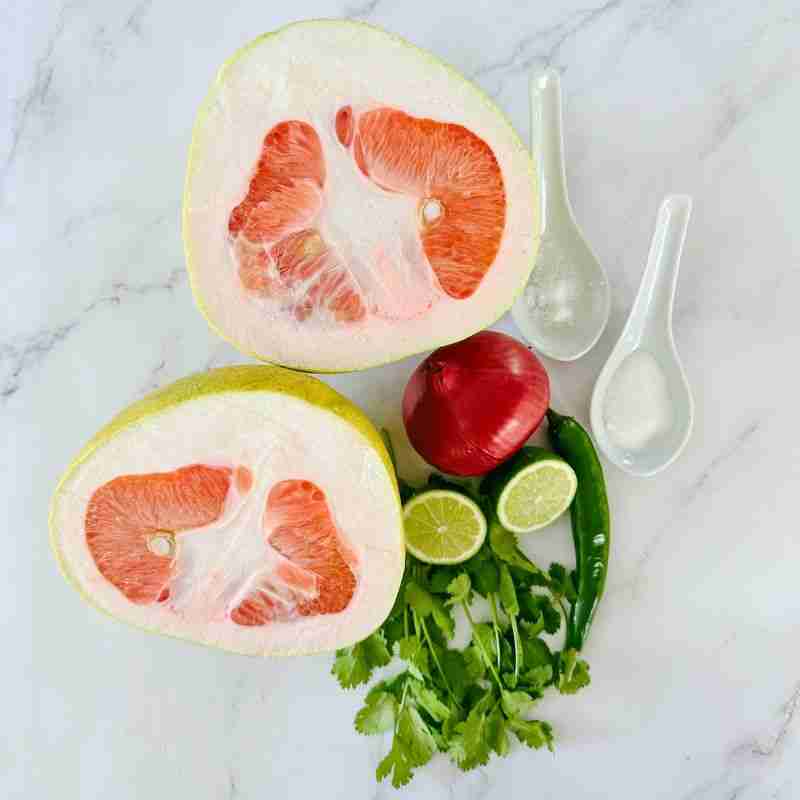 spicy pomelo salad ingredients includin pink pomelo, red onion, green chili. coriander cilantro, lime, salt and sugar