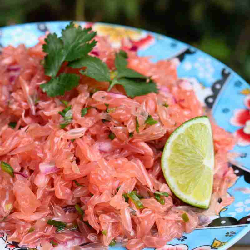 spicy pomelo salad on blue floral plate with wedge of lime