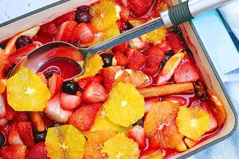 stewed orange compote with berries and spices in blue baking dish