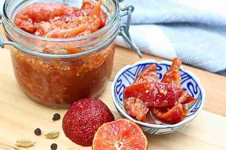 Australian blood lime pickle in jar and blue dish with blood lime halves on wooden board